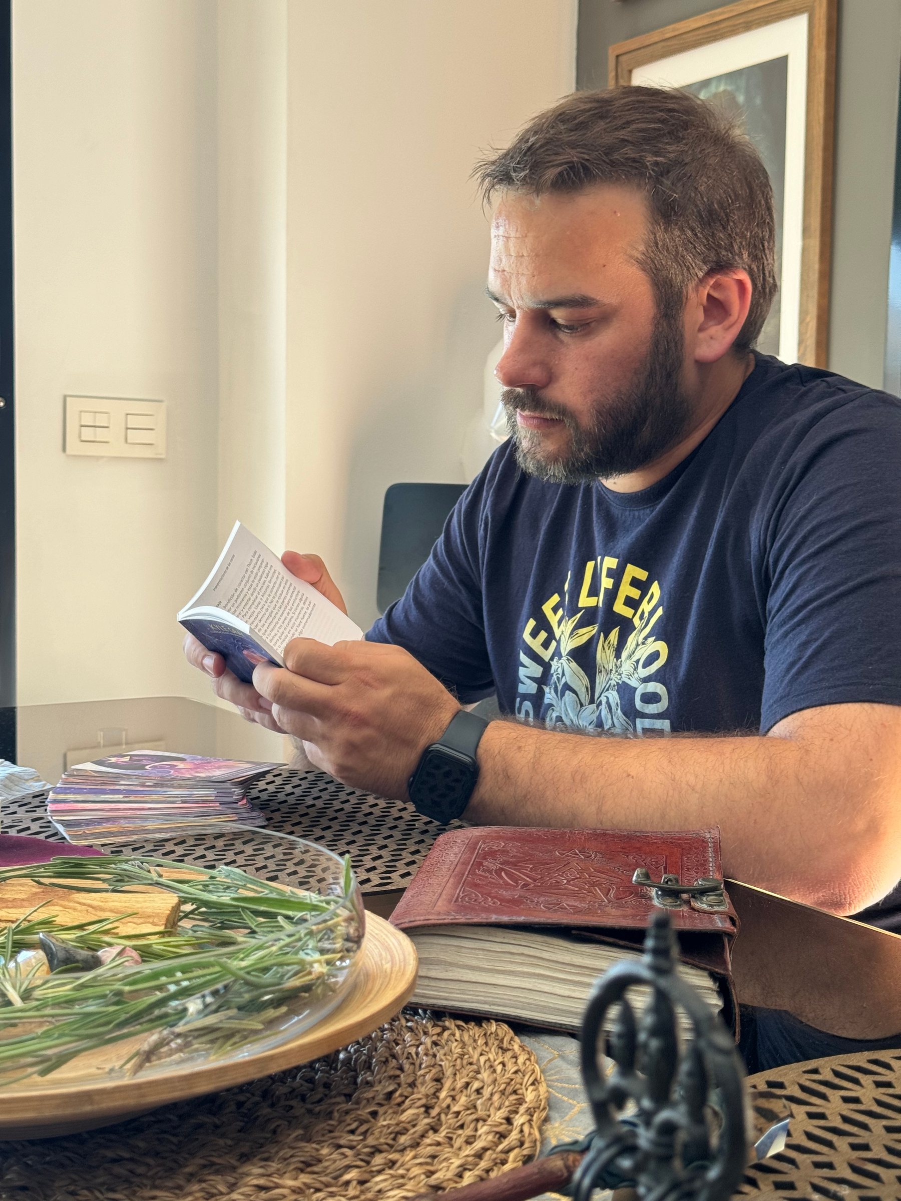 José leyendo junto a una bandeja con romero, palo santo y cartas